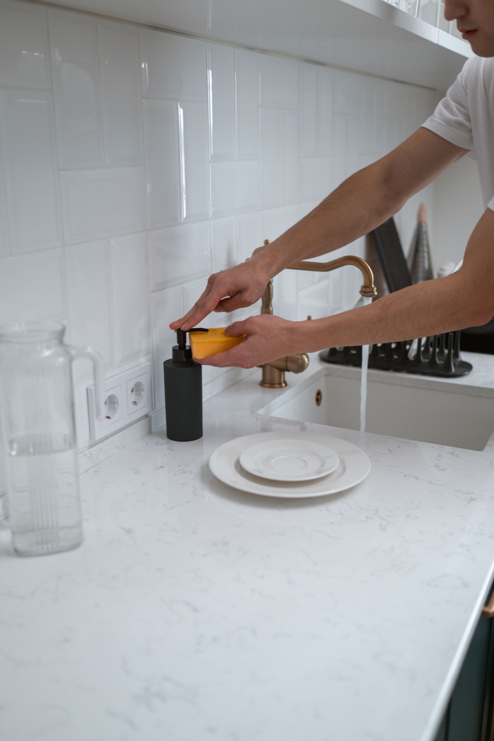A support worker washing dishes at a kitchen sink in a participant's home