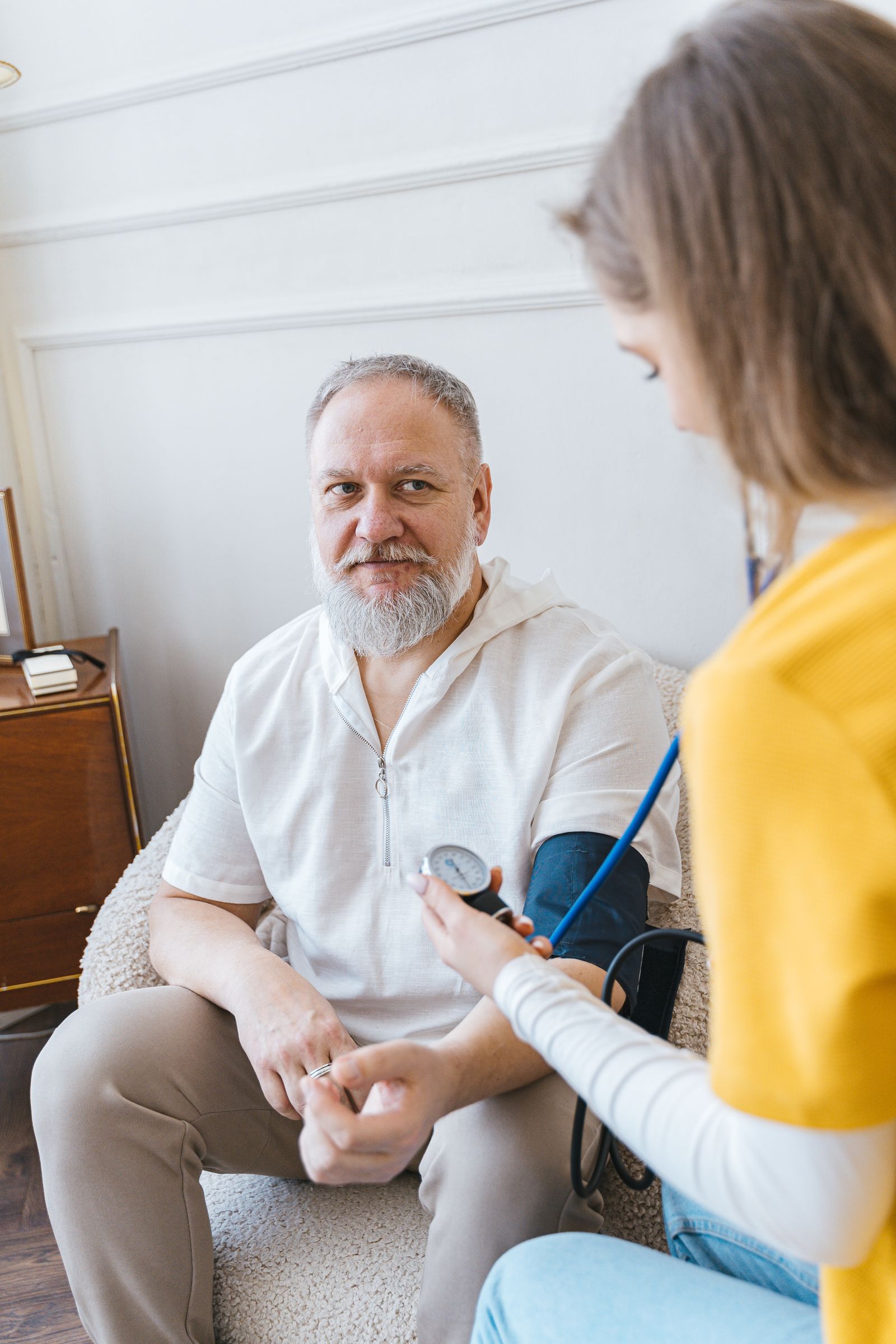 A nurse taking a man's blood pressure during a home visit
